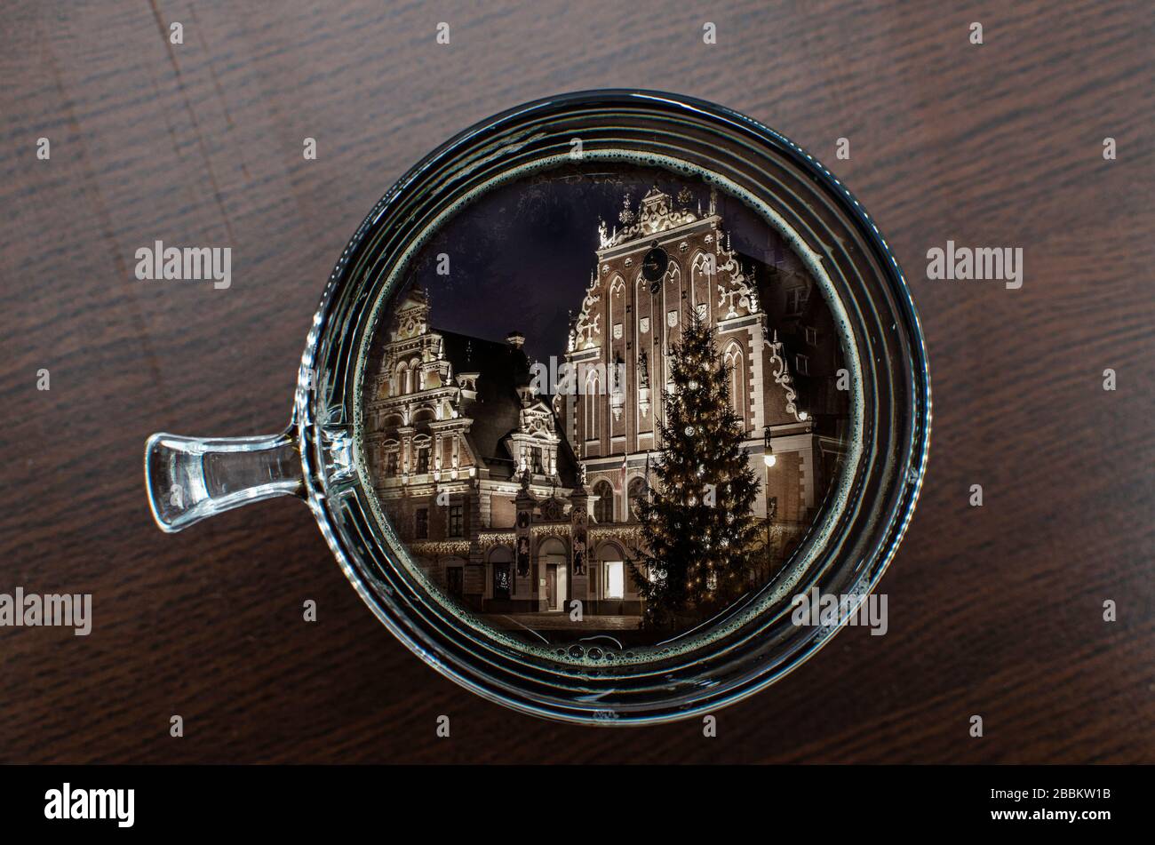 Vista superiore della tazza di caffè sul tavolo con la Casa delle teste nere con albero di Natale di notte in riflessione, la città vecchia riga, Lettonia Foto Stock