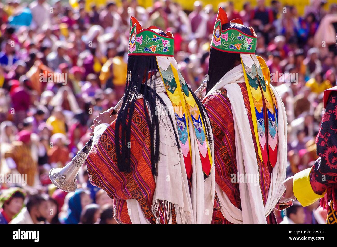 Le soffianti corno vestite con ricchi abiti rossi annunciano la processione al colorato festival Paro Tsechu Foto Stock