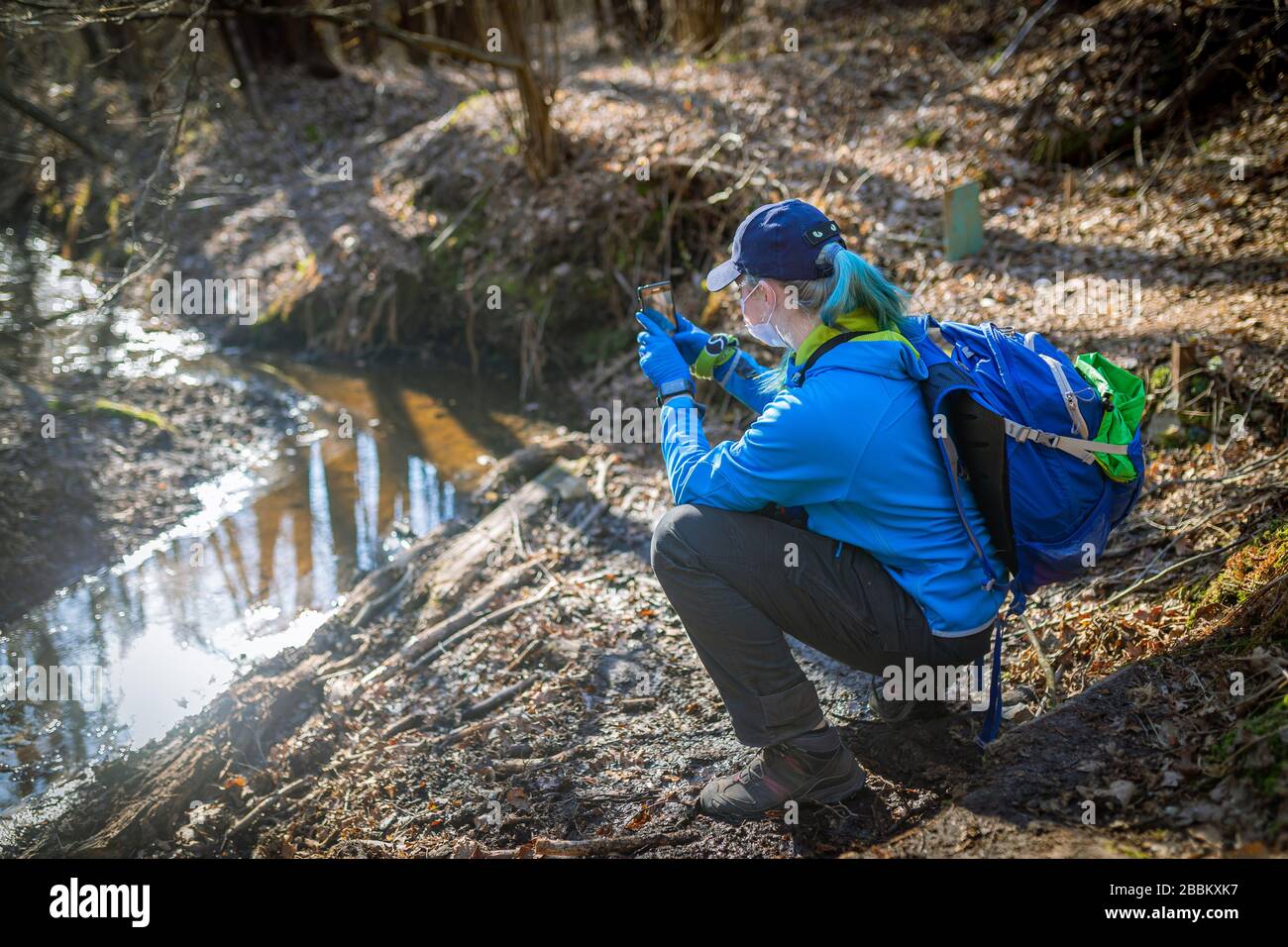 donna che spara un fiume nella foresta per telefono Foto Stock