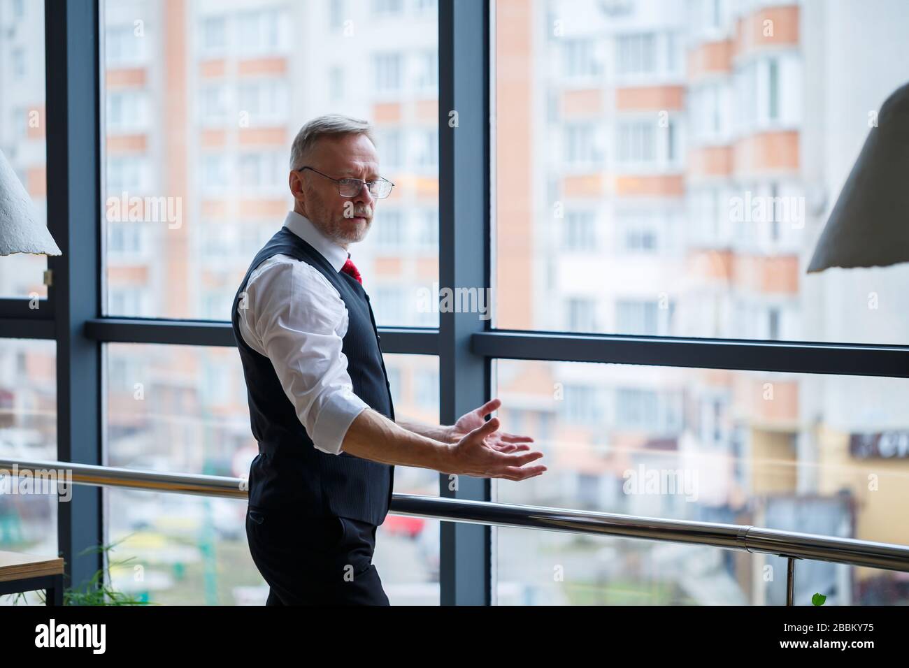 Sorridendo felice amministratore delegato pensa al suo successo di carriera sviluppo, mentre si trova in ufficio vicino allo sfondo di una finestra con copia sp Foto Stock