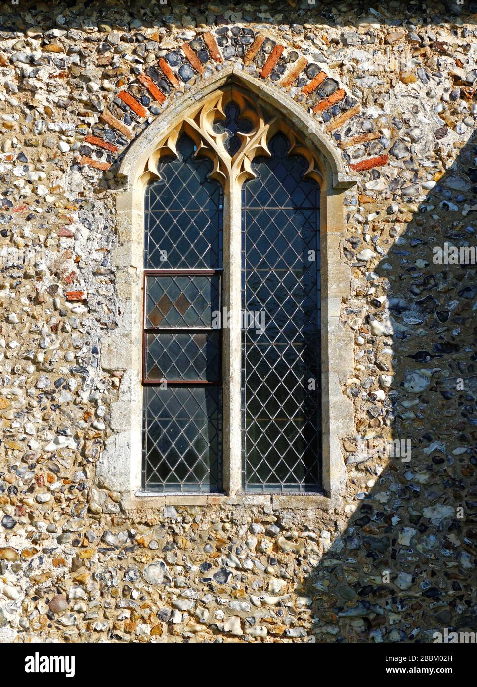 Dettaglio architettonico della finestra della navata sud con C19 restaurato testa nella chiesa parrocchiale di San Pietro a Ringland, Norfolk, Inghilterra, Regno Unito, Europa. Foto Stock