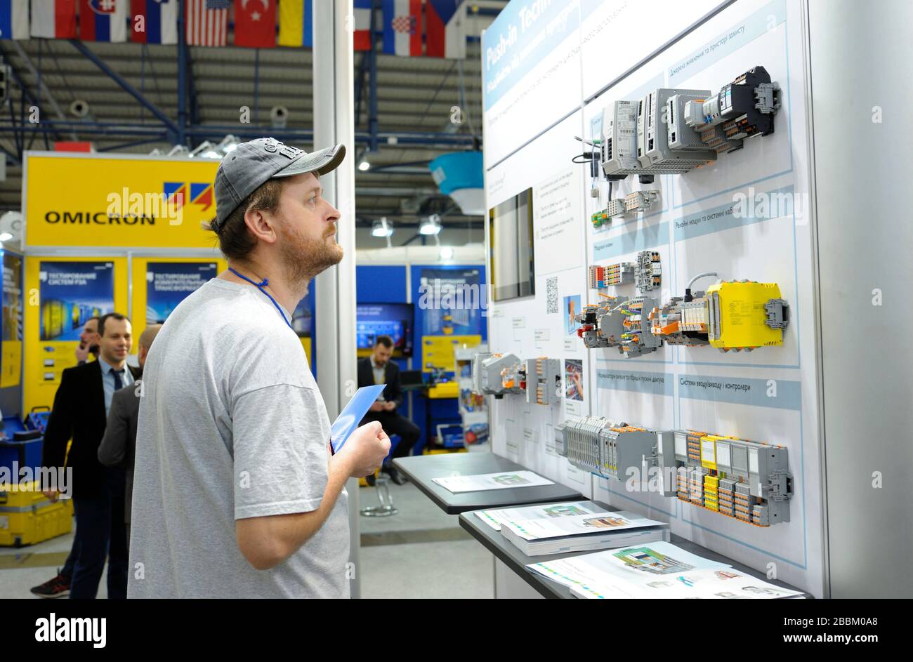 Il responsabile tocca il blocco del sistema di controllo automatico dell'alimentatore presentato sul supporto, spiegando al visitatore. Mostra industria Foto Stock