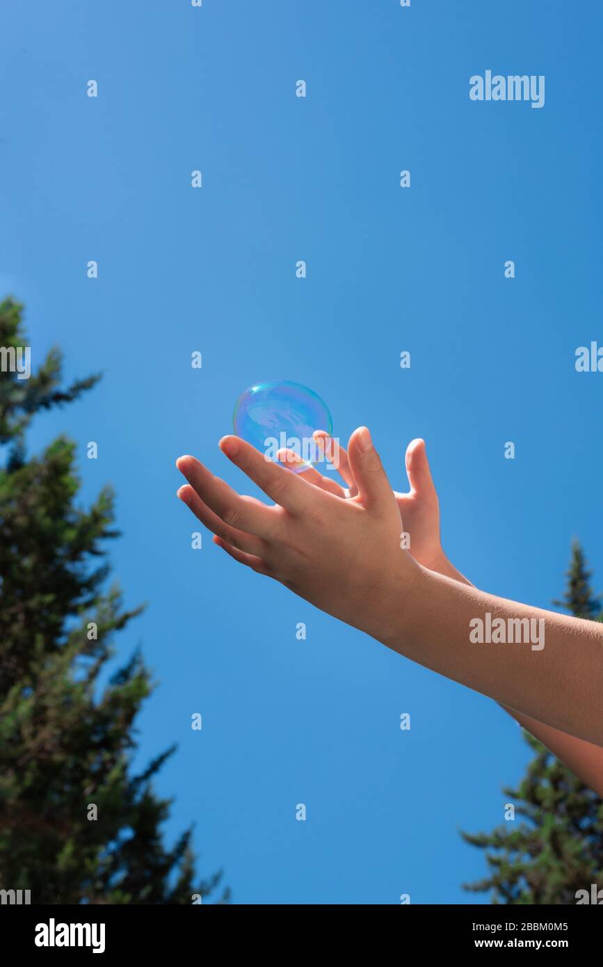 Un sapone bolle in bambini mani contro un cielo blu Foto Stock