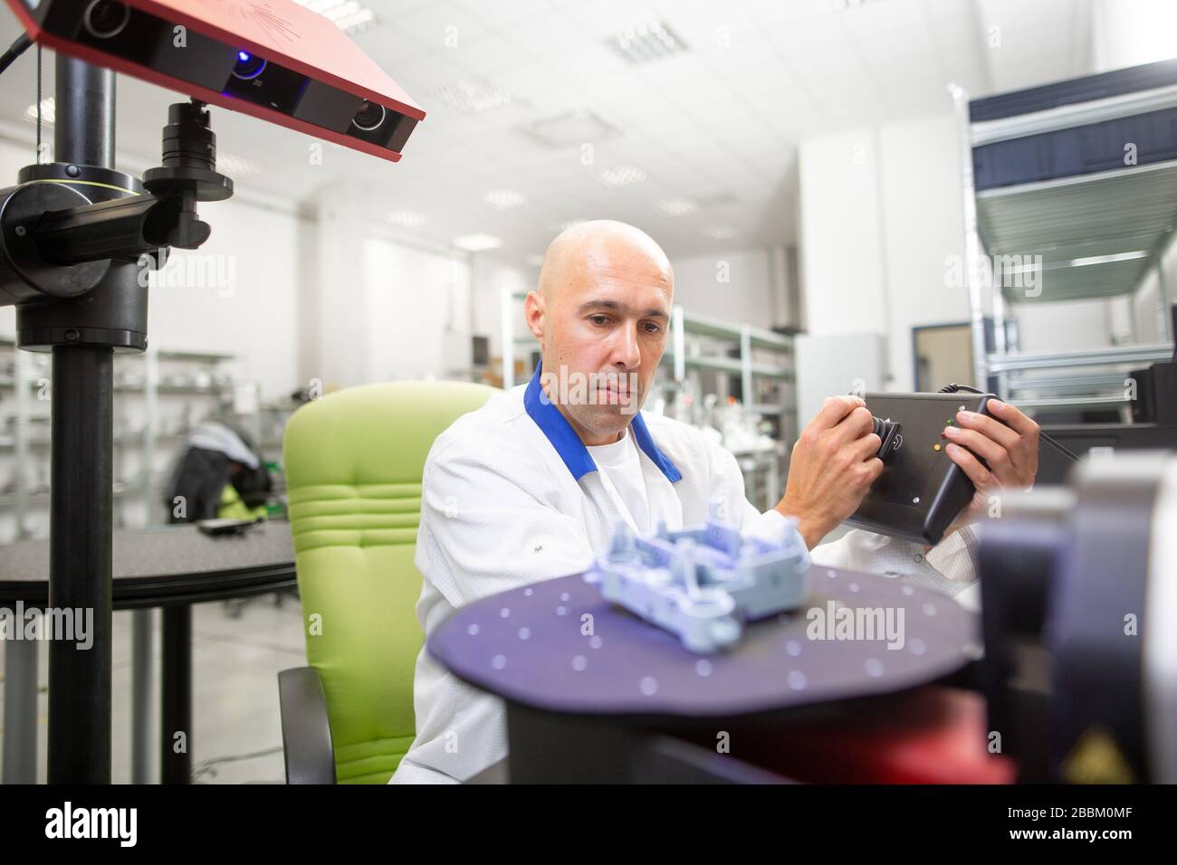 Tecnico di qualità che esegue la scansione di alcuni elementi stampati con scanner ottico 3D professionale, concetto automobilistico Foto Stock