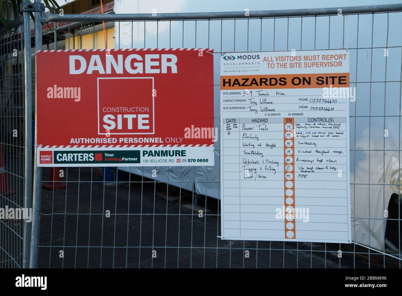 Pericolo, pericoli sul posto e segnali di salute e sicurezza su una recinzione metallica all'esterno di un edificio a St. Heliers, Auckland, Nuova Zelanda. Foto Stock