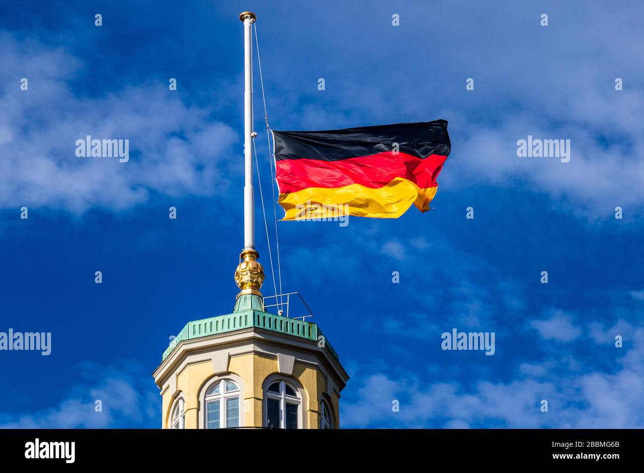 Vista dettagliata sulla bandiera tedesca a Halfmast, auf Halbmast, sul tetto della torre del castello di Karlsruhe, cielo blu sullo sfondo. Germania Foto Stock