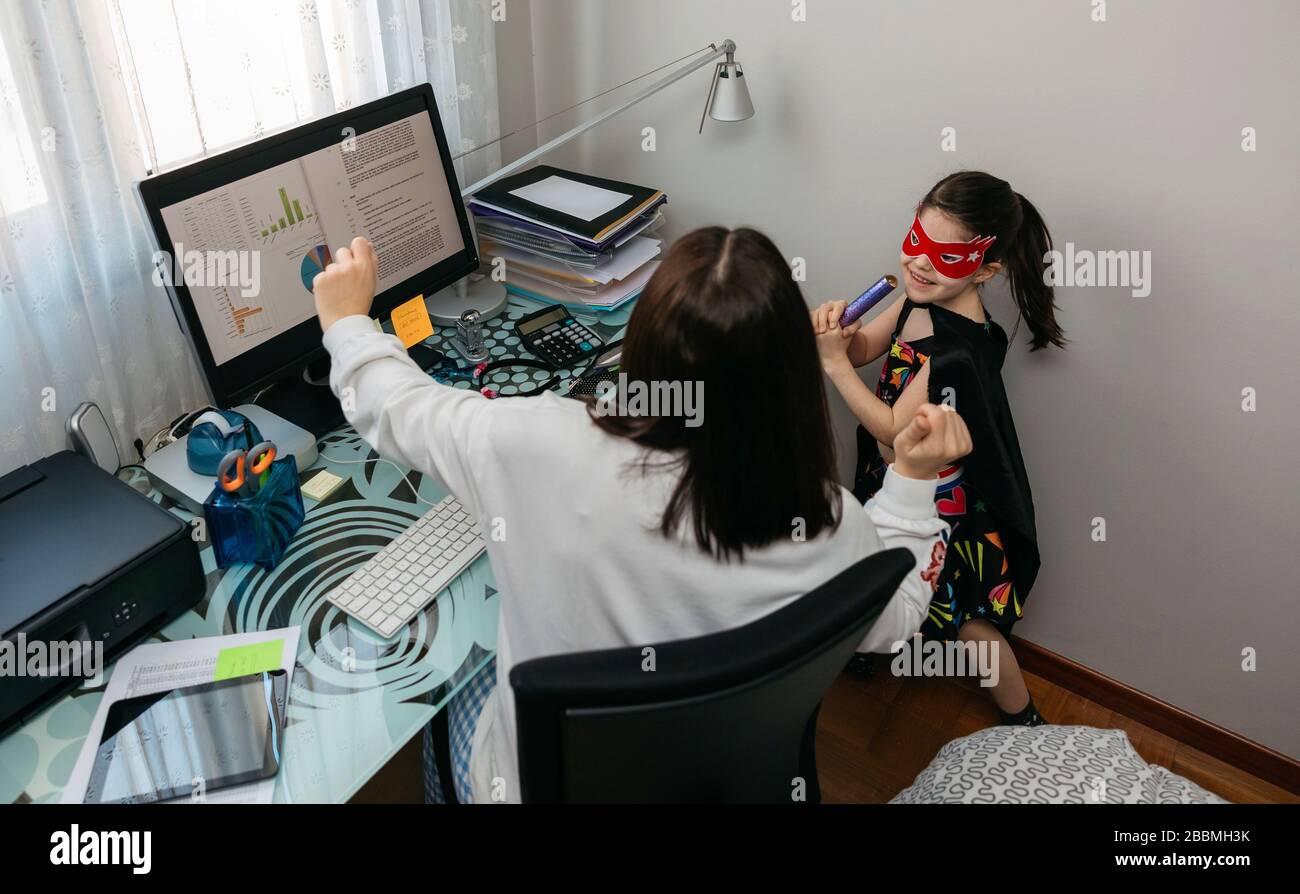 Donna che si telelavora con la figlia che balla con lei Foto Stock