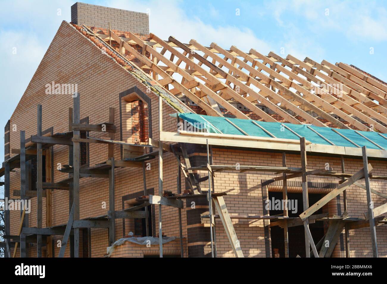 Costruzione di una struttura in legno sul tetto della casa. Costruzione di tetti incompleta casa tralicci tetto, barriera al vapore, travi in legno, eaves, legname Foto Stock