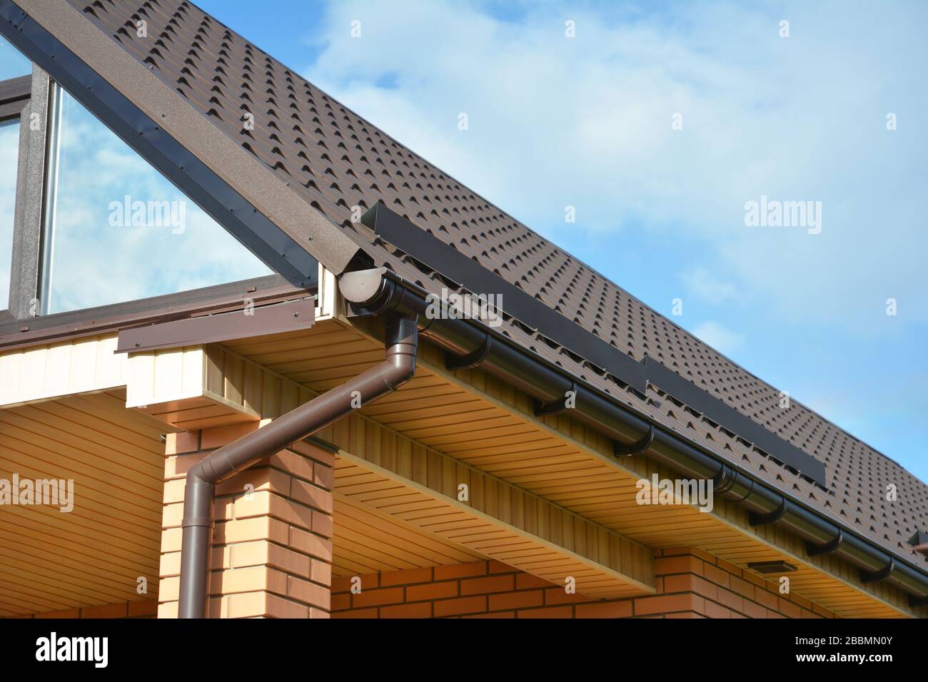Angolo tetto casa con soffitta panorama finestra lucernario e gocciolatoio pioggia con tubo discendente. Foto Stock