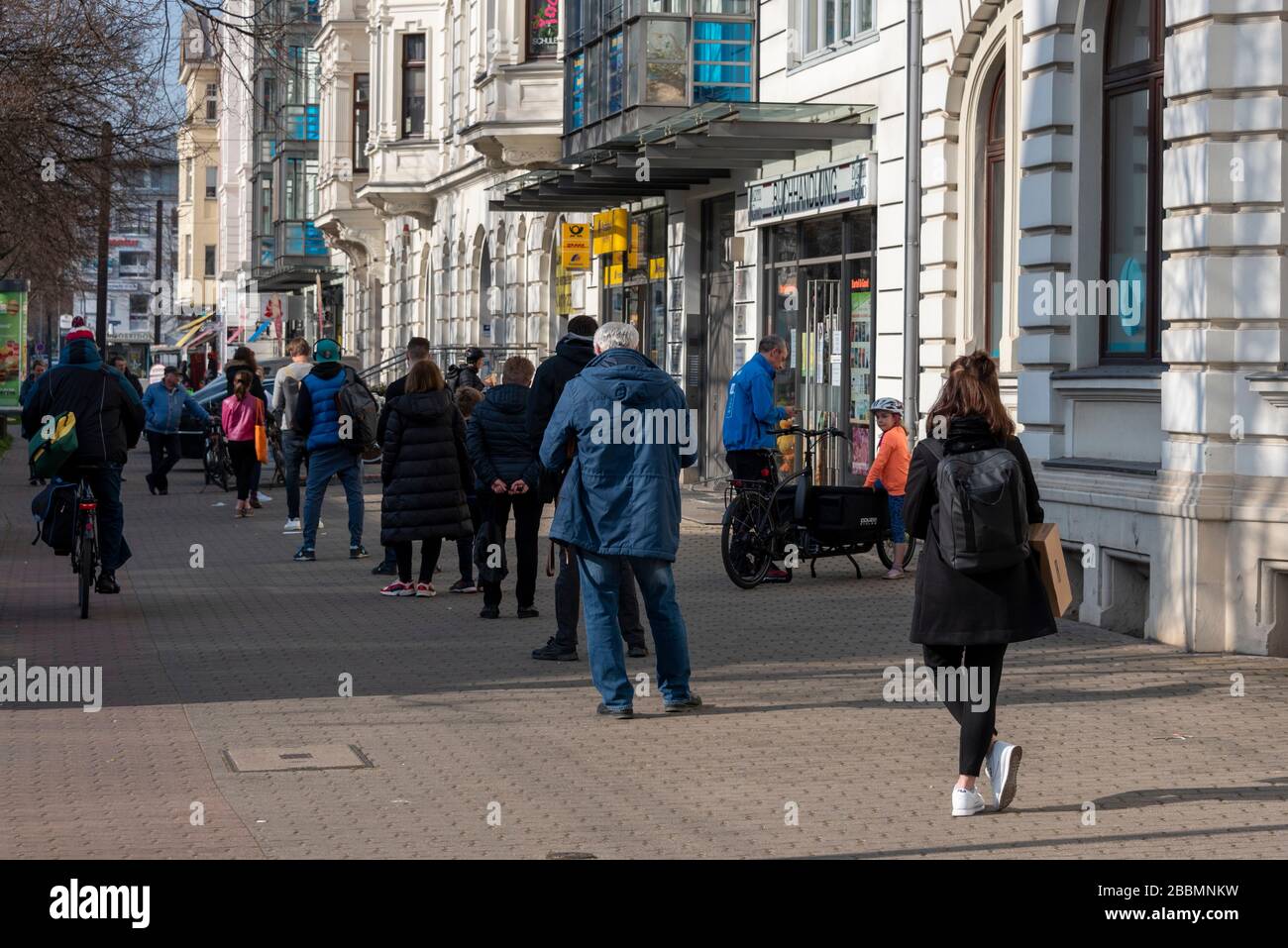 Magdeburg, Germania. 27th Mar, 2020. Una lunga coda si è formata di fronte ad un ufficio postale nel quartiere Stadtfeld. La gente sta mantenendo una distanza minima di due metri a causa della crisi del Corona. Ciò dovrebbe ridurre il rischio di contrarre il virus. Credito: Stephan Schulz/dpa-Zentralbild/ZB/dpa/Alamy Live News Foto Stock