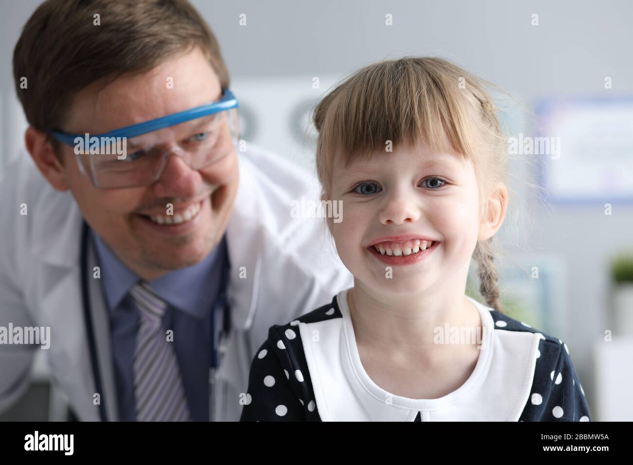 Sorridente medico maschile che guarda sano felice bambino Foto Stock