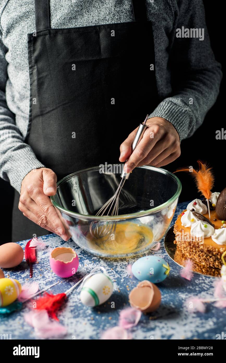 L'uomo la preparazione di un tipico mona de Pascua, una torta mangiata in Spagna il lunedì di Pasqua, decorato con un uovo di cioccolato, un pulcino di peluche e piume di differenti Foto Stock