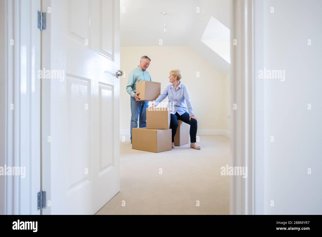 Riduzione di coppia senior nelle scatole di trasporto di pensione in nuova casa durante il giorno moving Foto Stock