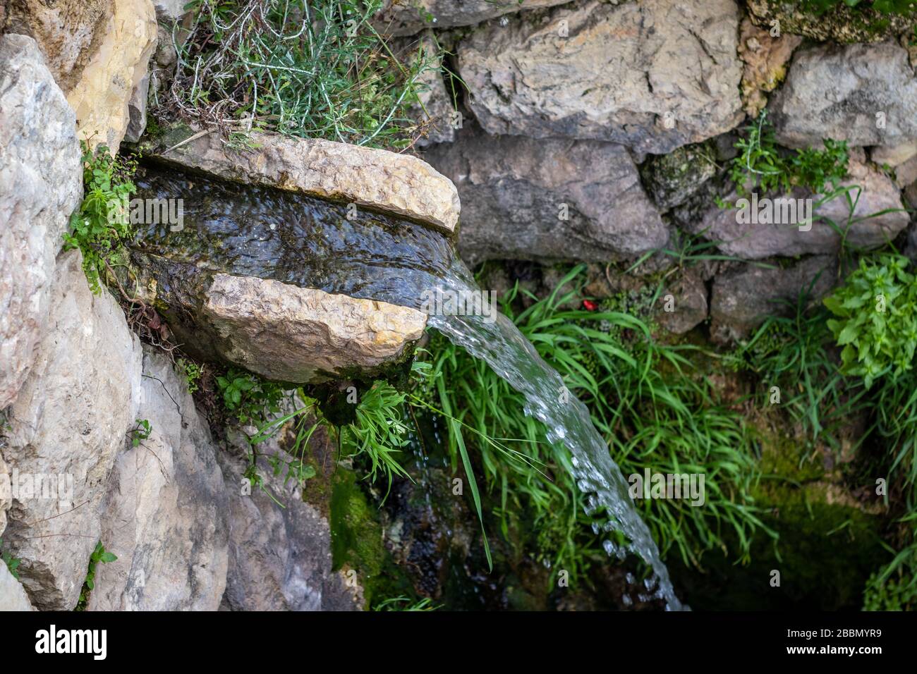 Una piccola cascata che cade in un'antica piscina di stoccaggio dalla sorgente di sataf, ai piedi di una città vecchia abbandonata, utilizzata per irrigare e lavare cl Foto Stock