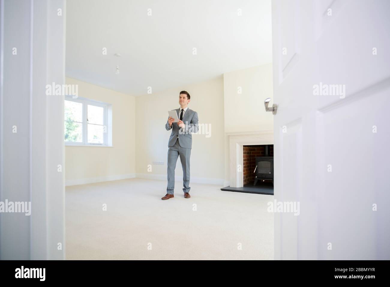 Realtor con il tablet digitale che guarda intorno e valorizza la nuova casa Foto Stock