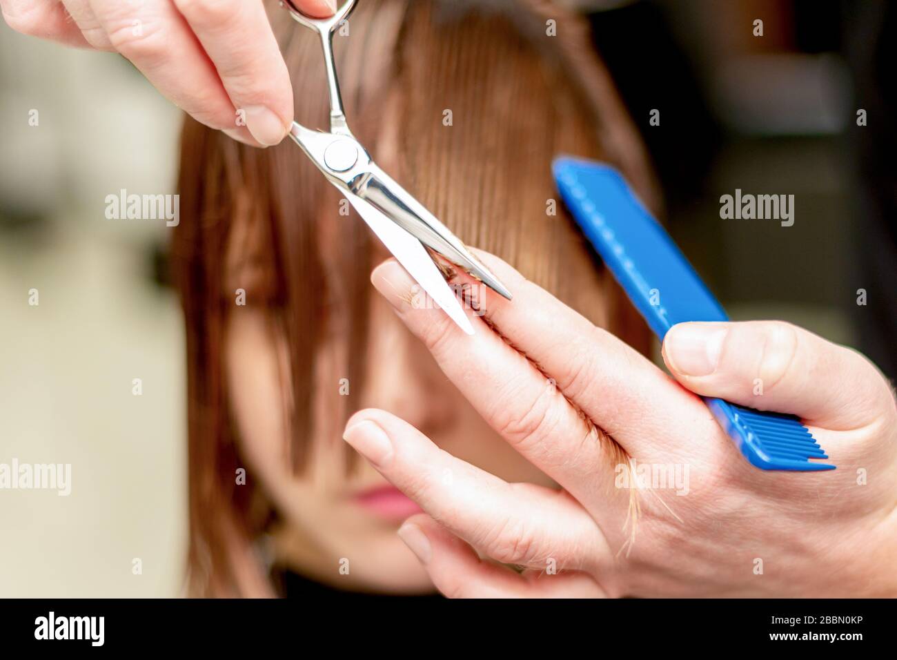 Mani di parrucchiere tagli capelli punte di donna nel salone di bellezza. Tonato. Foto Stock