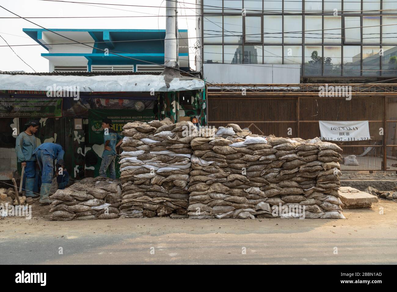 Jakarta, Indonesia - 13 luglio 2019: Un gruppo di addetti alla manutenzione lavorano rudimentaryly scavando fossati, riempendo sacchi di suolo e fissando tubi di liquame. Foto Stock