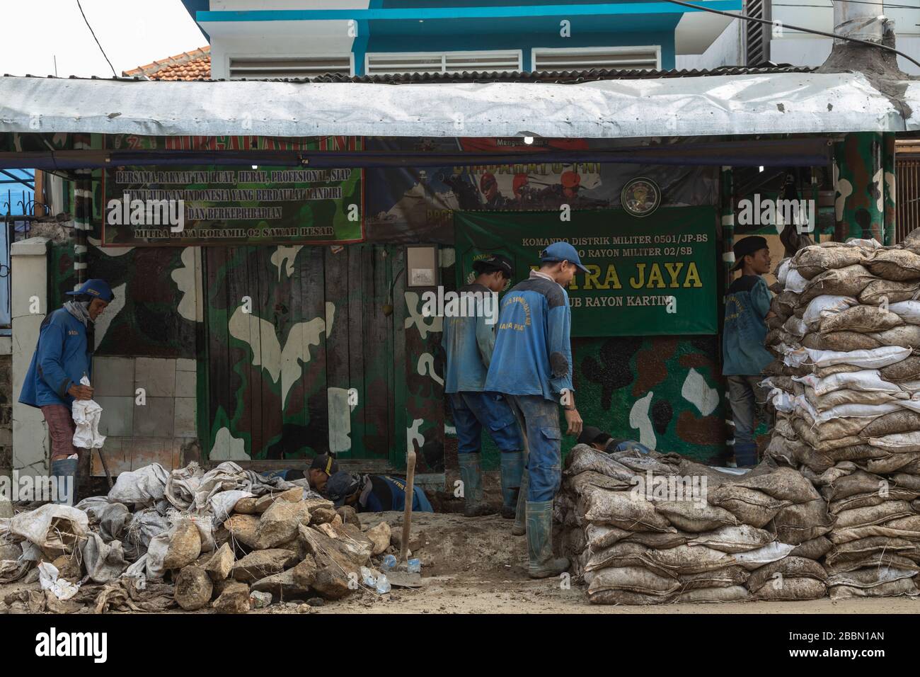 Jakarta, Indonesia - 13 luglio 2019: Un gruppo di addetti alla manutenzione lavorano rudimentaryly scavando fossati, riempendo sacchi di suolo e fissando tubi di liquame. Foto Stock