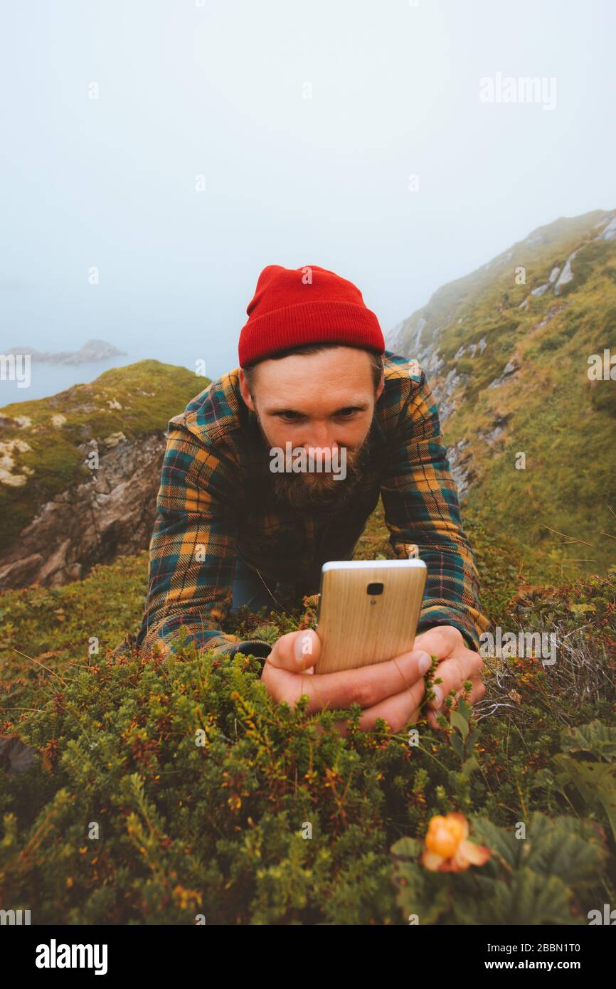Uomo che usa lo smartphone scattare foto di cloudberry camminare all'aperto tecnologia moderna influenzatore blogger stile di vita vacanze estive in Norvegia Foto Stock