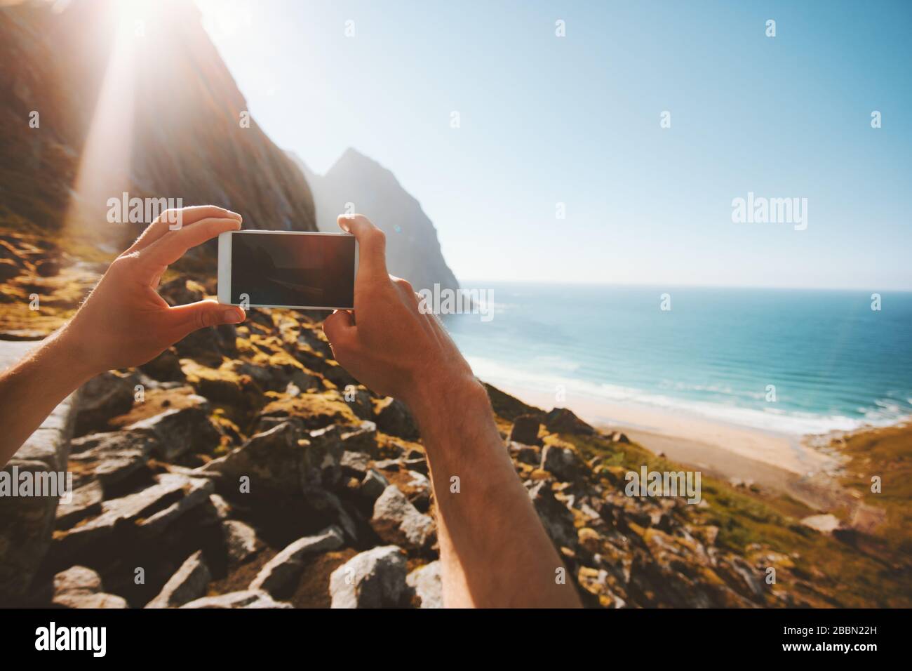 Blogger di viaggio scattare foto da smartphone influenzatore stile di vita vacanze estive social media creazione di contenuti all'aperto mare Kvalvika spiaggia paesaggio in Foto Stock