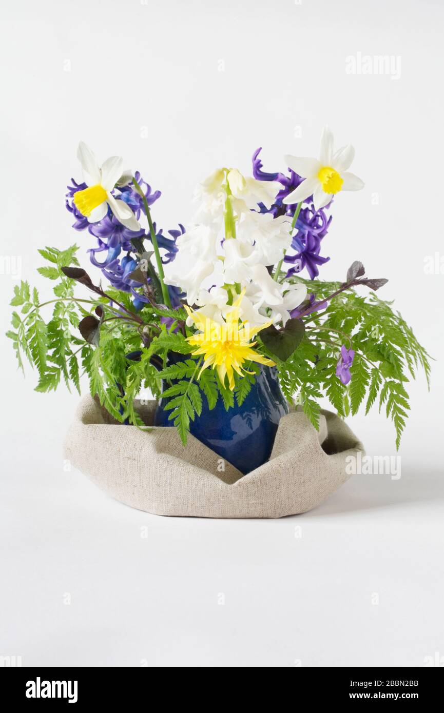 Fiori primaverili in una brocca blu. Giacinti, narcisi e violetti. Foto Stock