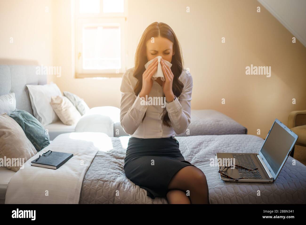 Donna d'affari ha lavorato molto per un viaggio d'affari, seduto in camera e lavorando su un computer portatile. Sta avendo allergia. Foto Stock