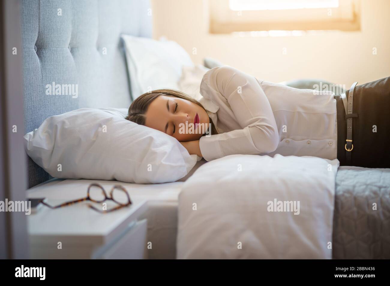 Una donna d'affari stanca dorme vestita in camera d'albergo. Foto Stock
