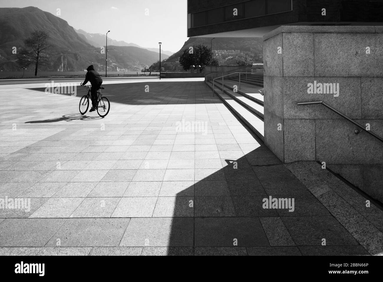 Un uomo guida una bicicletta in una grande piazza. Foto in bianco e nero Foto Stock