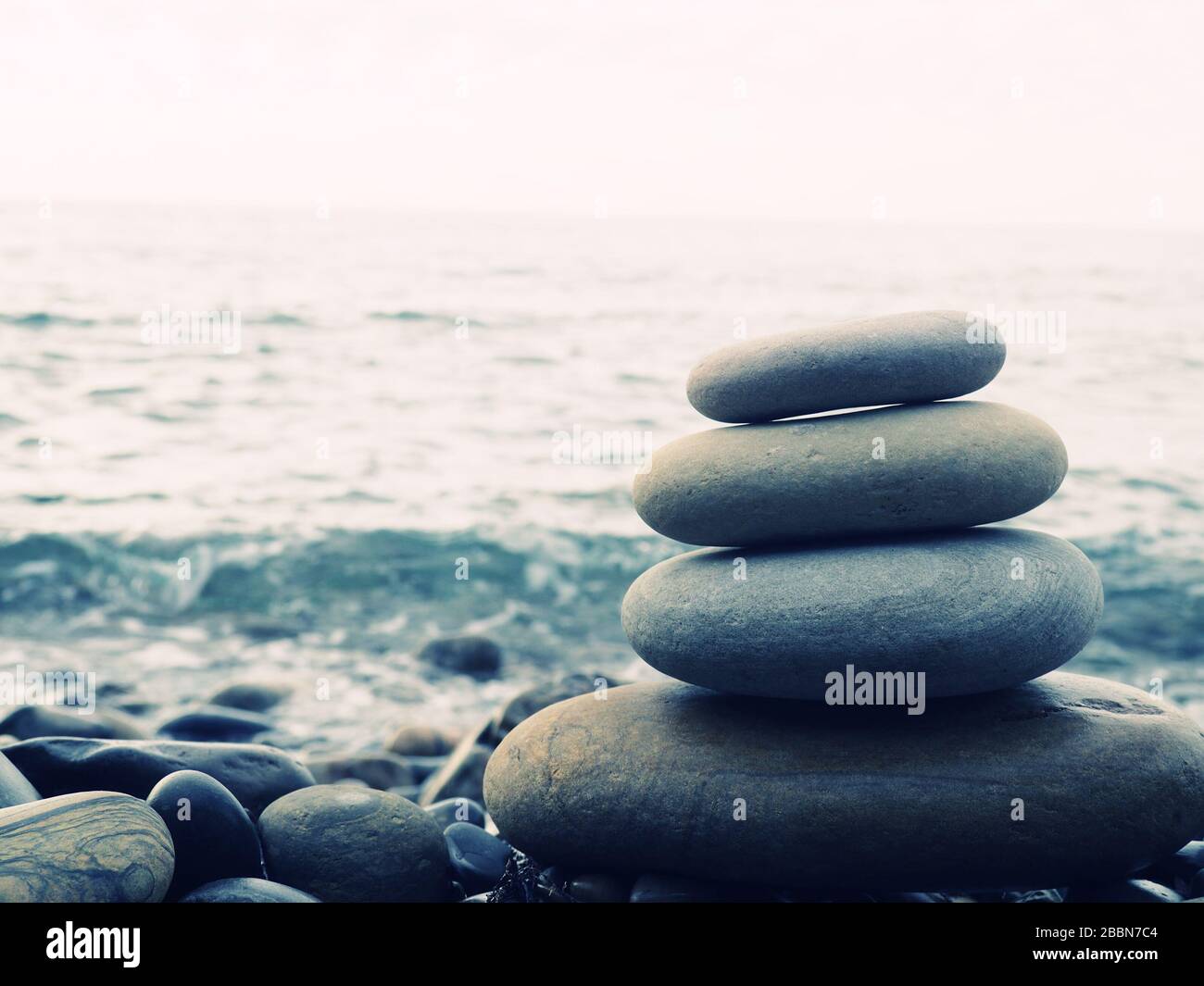 Equilibrio, tranquillità, diverse dimensioni pietre formano una piramide, pietre piramide sulla spiaggia di ghiaia simboleggia stabilità, zen, armonia, equilibrio. Bassa de Foto Stock