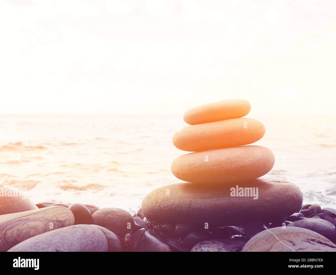 Equilibrio, tranquillità, diverse dimensioni pietre formano una piramide, pietre piramide sulla spiaggia di ghiaia simboleggia stabilità, zen, armonia, equilibrio. Bassa de Foto Stock
