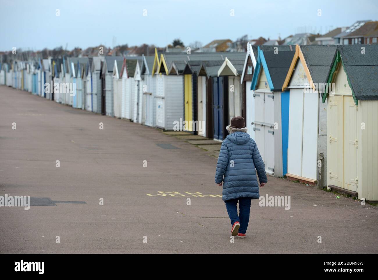 Una donna cammina oltre le capanne sulla passeggiata a Southend, Essex, come il Regno Unito continua in blocco per aiutare a frenare la diffusione del coronavirus. Foto Stock