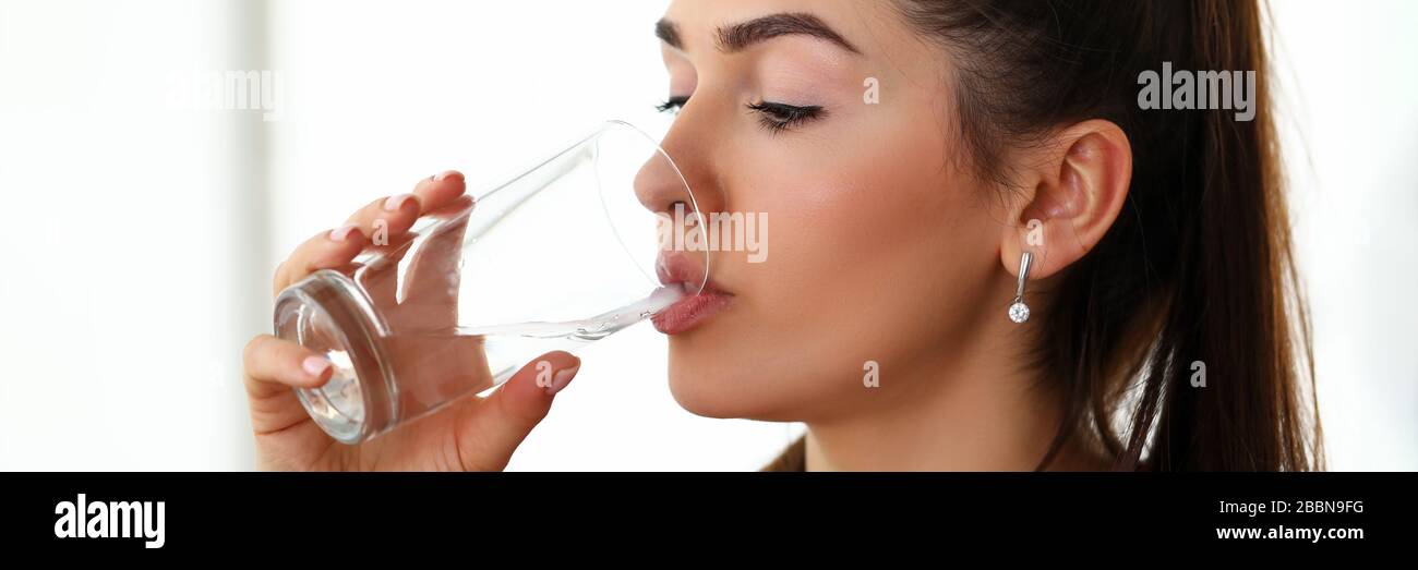 Bella ragazza al lavoro beve acqua dal vetro Foto Stock