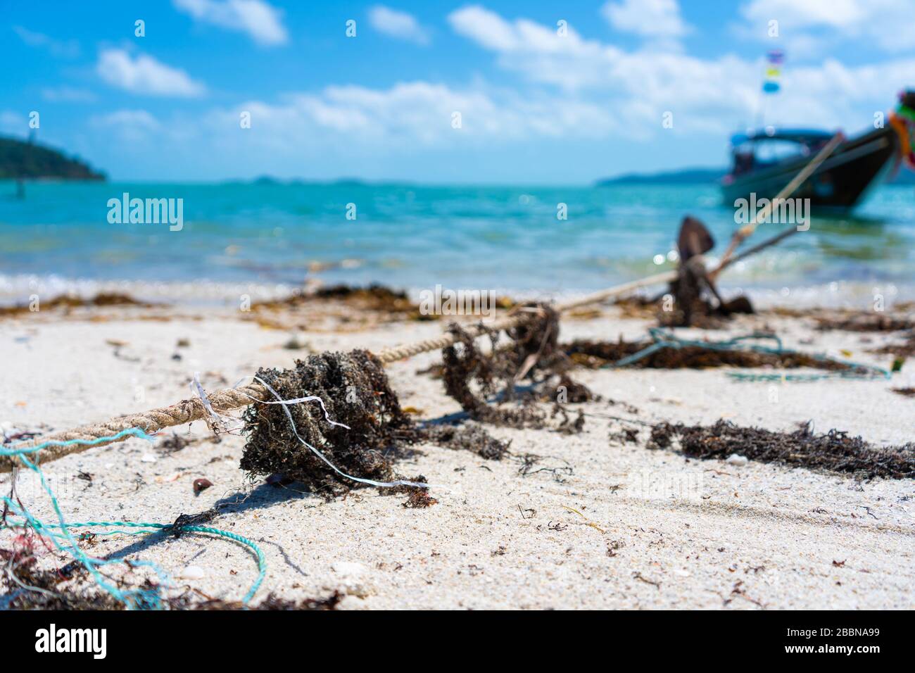 Corda da primo piano per ormeggiare una barca sulla spiaggia, in alghe secche Foto Stock