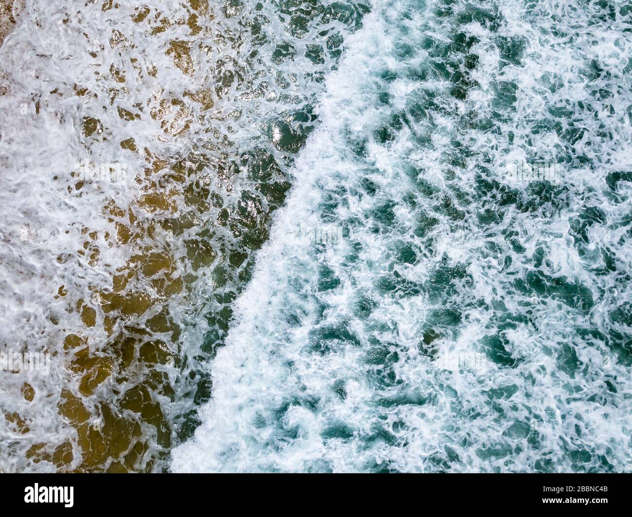 Vista aerea con droni delle onde oceaniche che si infrangono sulla costa tropicale di Bali, Indonesia Foto Stock