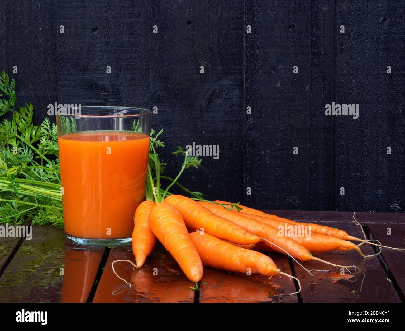 Primo piano di succo di carota fatto in casa con carote biologiche a tavola Foto Stock