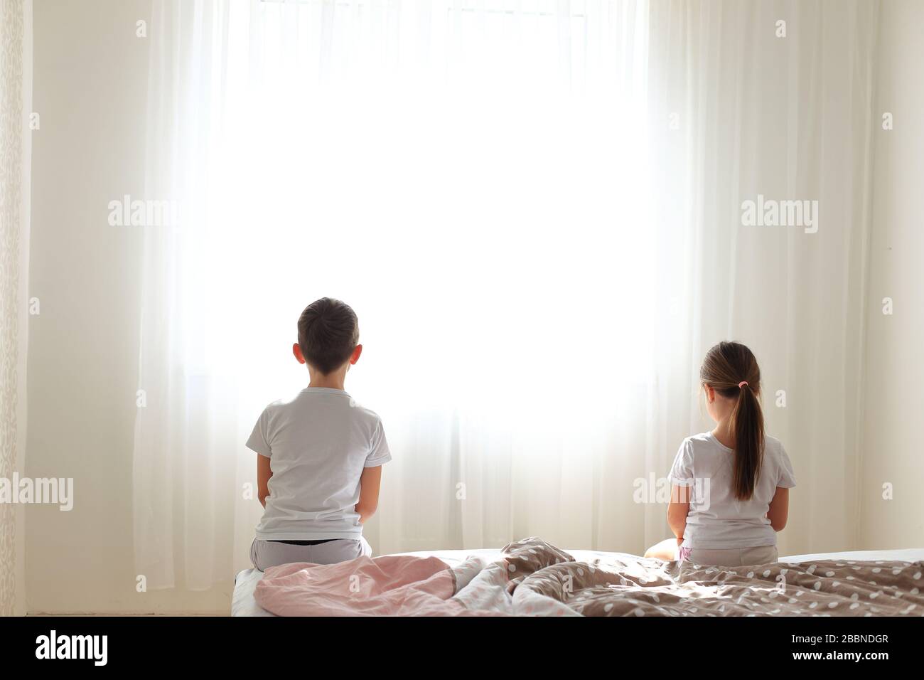 Ragazzo e ragazza sono seduti sul letto a distanza l'uno dall'altro. Foto Stock