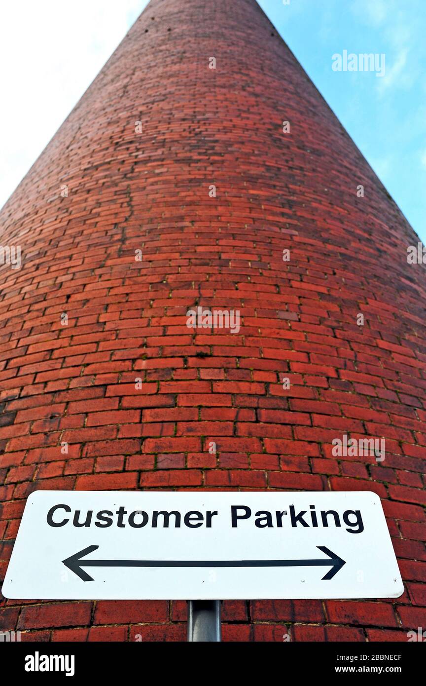 Cartello per il parcheggio dei clienti ai piedi del vecchio camino del mulino di cotone e filatura ex mulino, Preston, Regno Unito Foto Stock