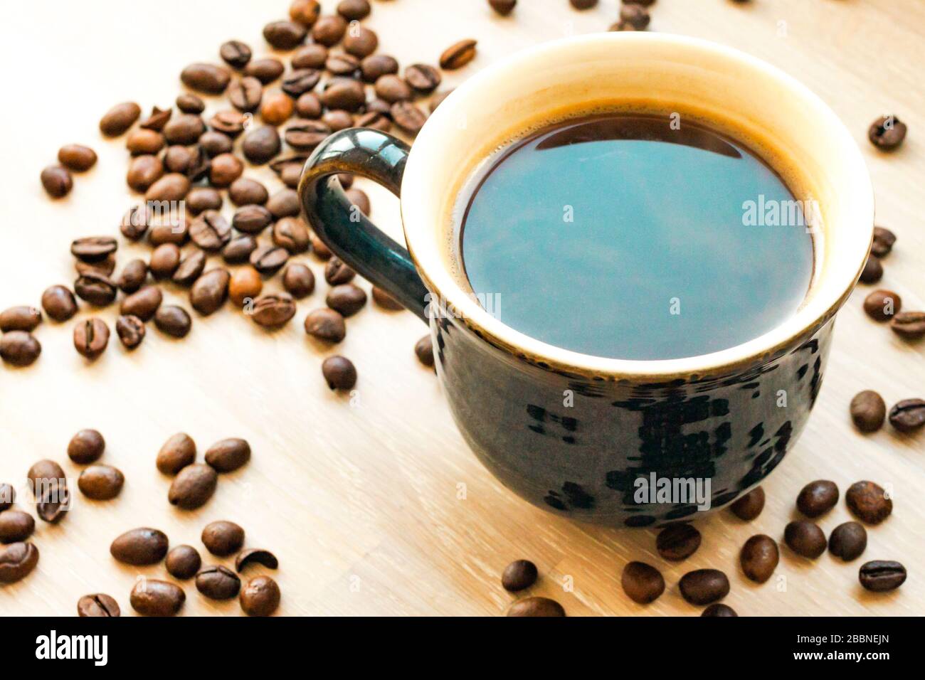 Caffè bean tazza primo piano su sfondo di legno naturale chiaro. Colazione al mattino Foto Stock