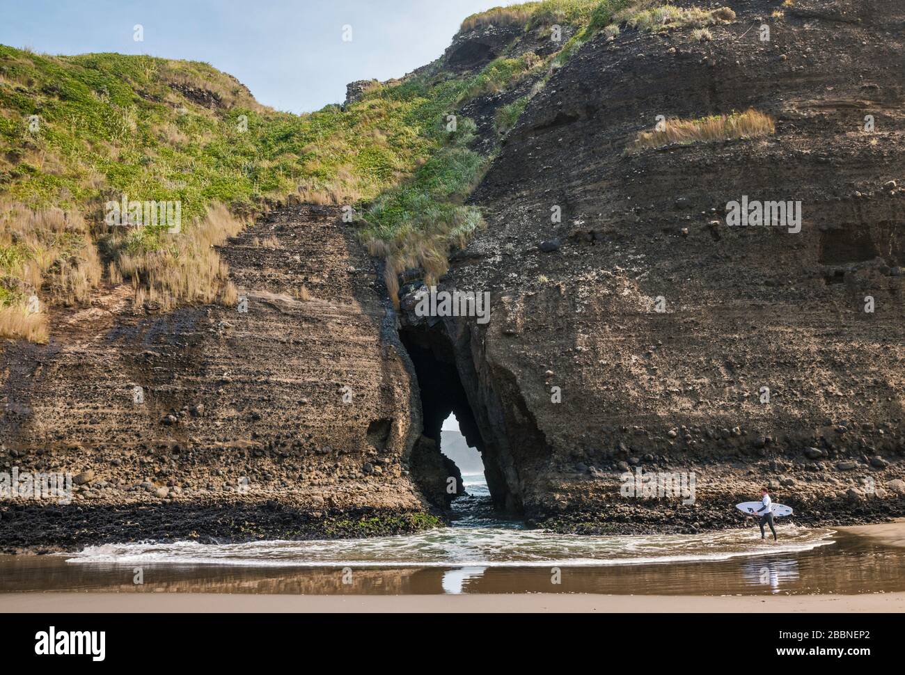 Surfer che si avvicina al Gap, al Rock di Taitomo, al Lookout Track di Tasman, al Waitakere Ranges Regional Park, vicino alla spiaggia di Piha, all'Isola del Nord, alla Nuova Zelanda Foto Stock