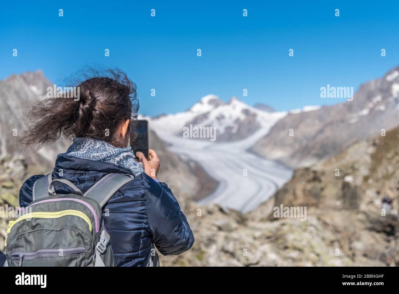 Vista posteriore della donna che fotografa il ghiacciaio di Aletsch con smartphone dal punto di vista Eggishorn Foto Stock