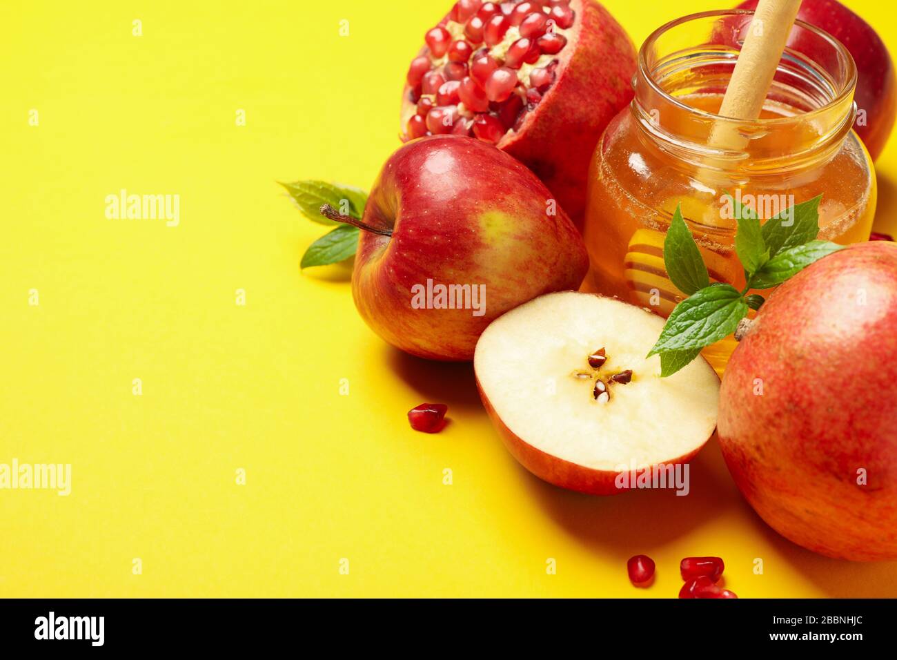 Mela, miele e melograno su sfondo giallo, spazio per il testo Foto Stock