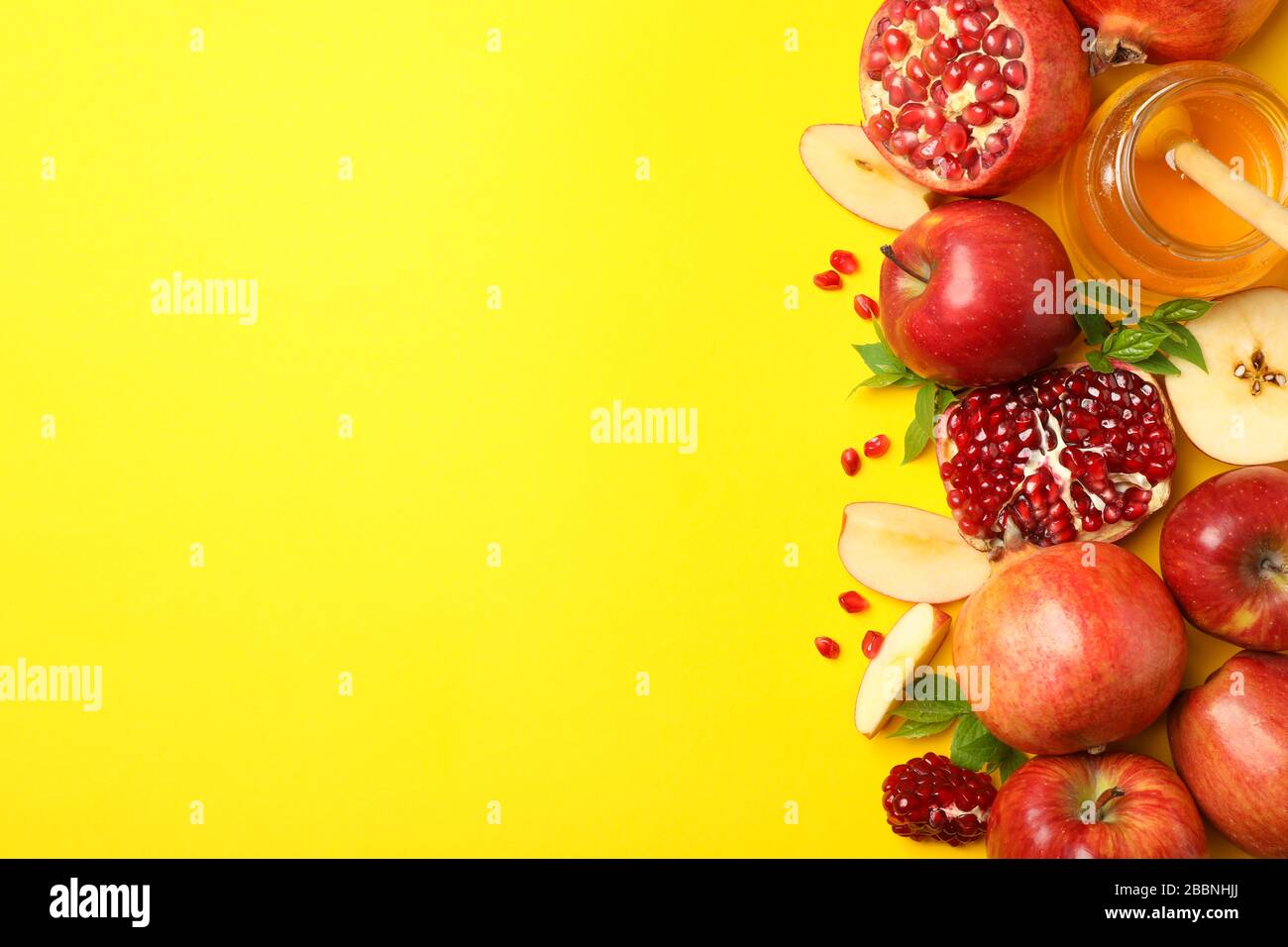 Mela, miele e melograno su sfondo giallo, spazio per il testo Foto Stock