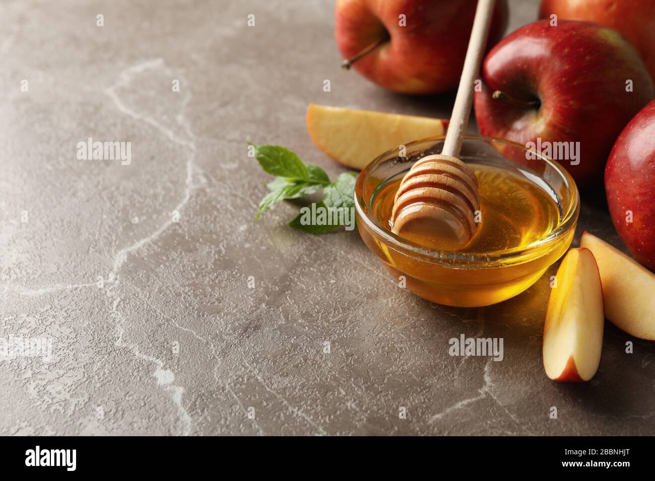Mele e miele su sfondo grigio, spazio per il testo Foto Stock