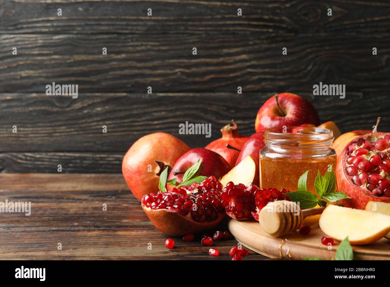 Mele, melograno e miele su sfondo ligneo, spazio per il testo Foto Stock