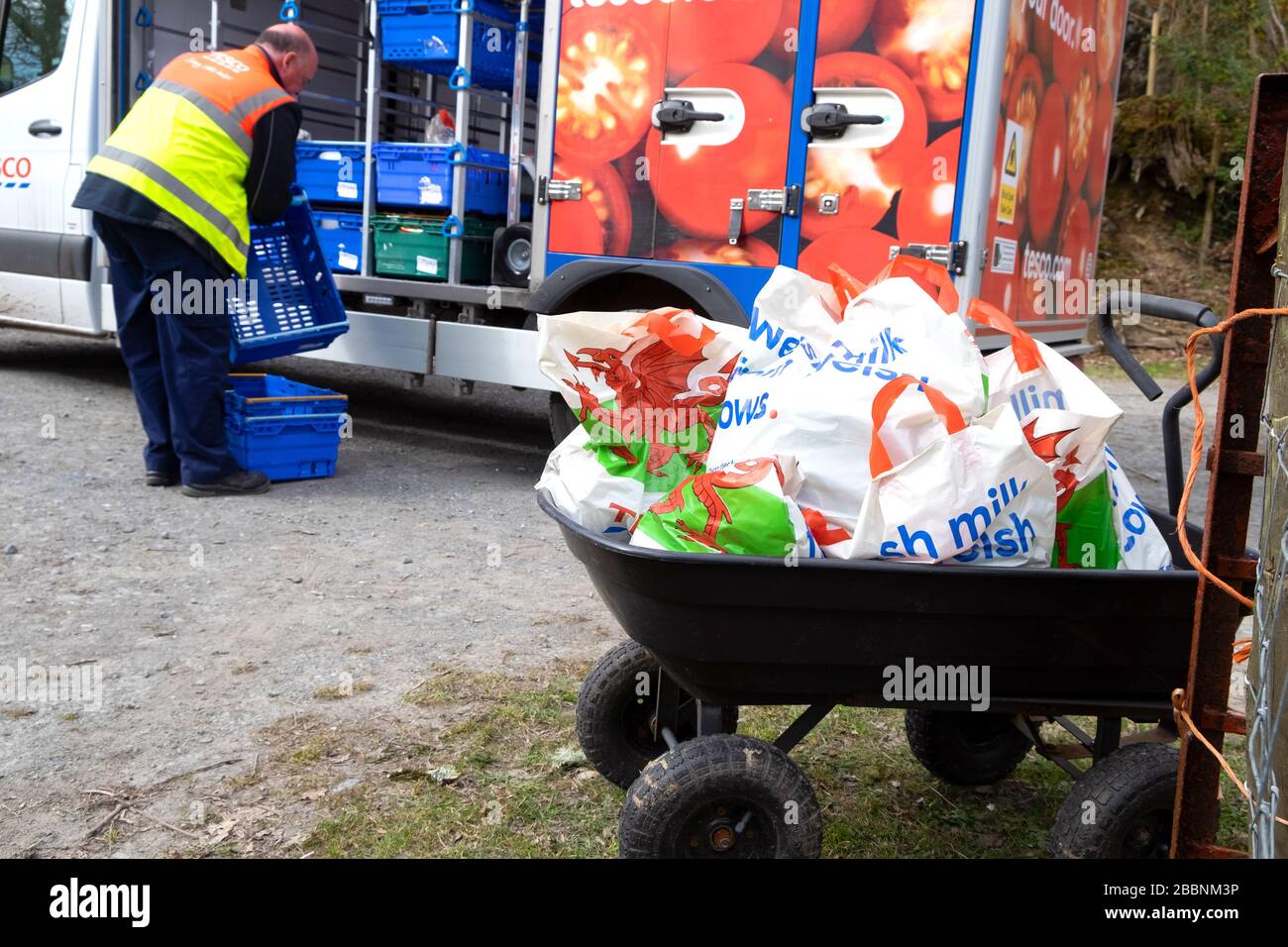 Tesco food van driver consegna generi alimentari in sacchetti di plastica a una persona più anziana auto-isolante nel Galles rurale durante il Coronavirus Wales UK 2020 Foto Stock