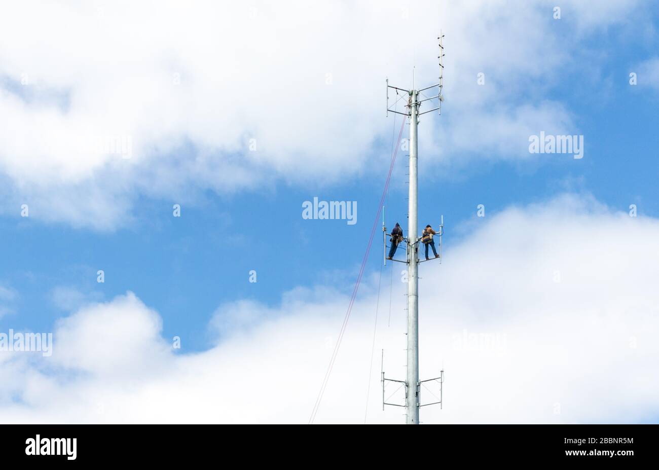 Due uomini che lavorano su una torre radiofonica sopra il reparto di fuoco dell'isola di Shelter a Shelter Island, NY Foto Stock