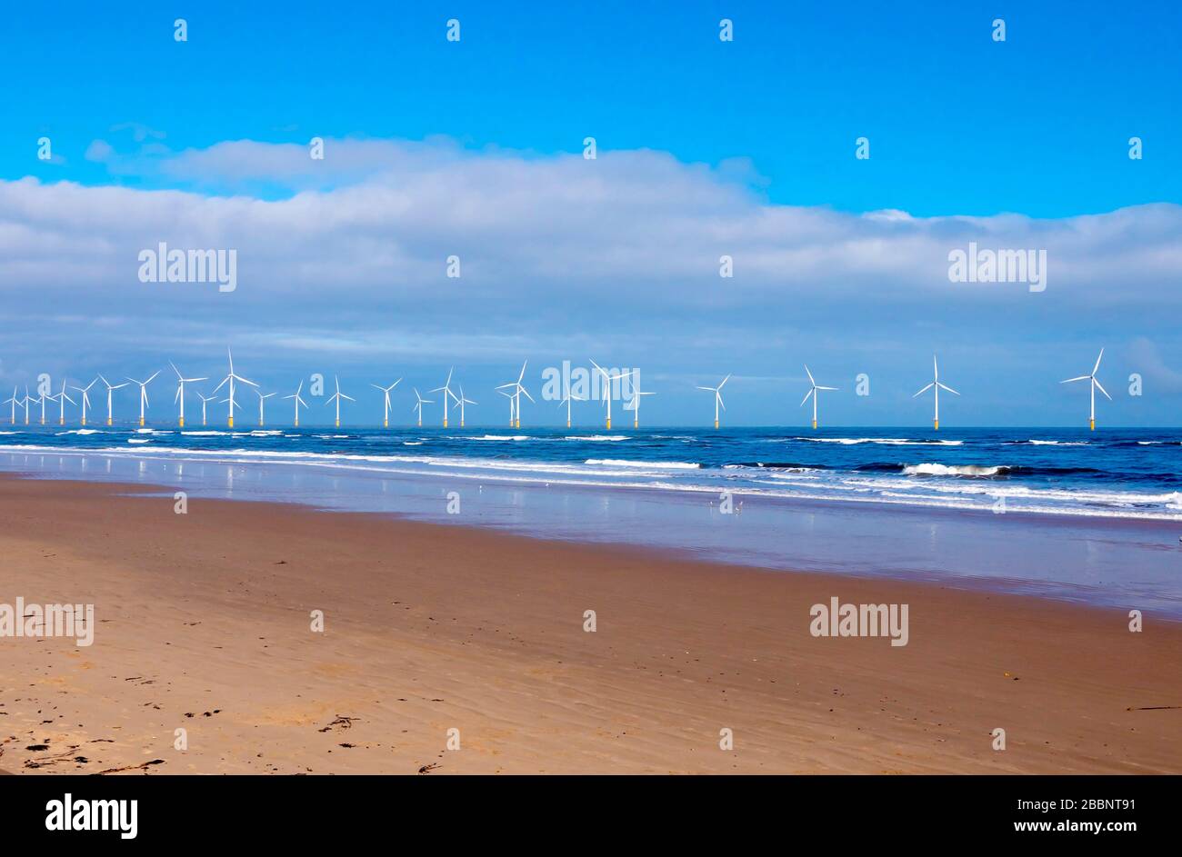 Sun Lit Redcar Wind Farm dalla spiaggia deserta con tutte le 27 turbine eoliche mostrate Foto Stock