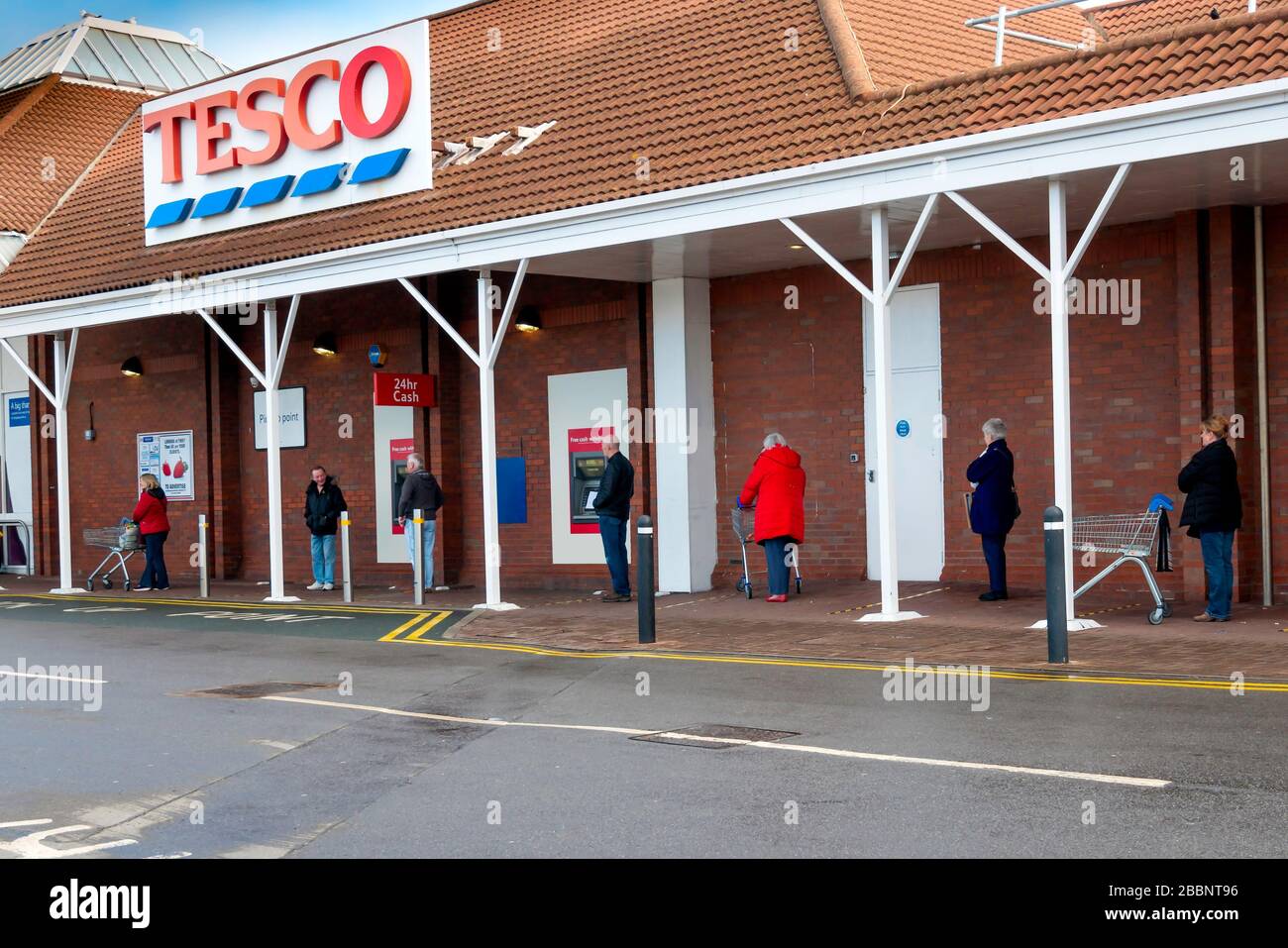 Una coda di persone in attesa di entrare in un supermercato Tesco sono distanziati di 2 metri come distanza sicura durante la pandemia di Coronavirus o Covi9 19 Foto Stock