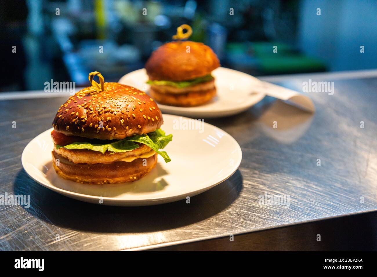 Pasti pronti hamburger al banco per la consegna ai camerieri in un ristorante e cucina in background Foto Stock