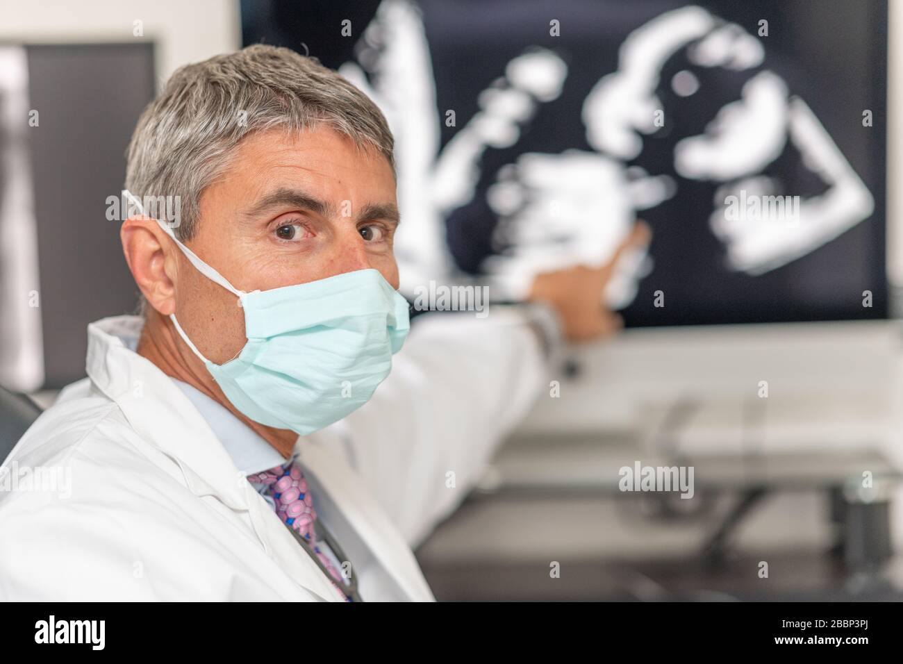 Uomo medico indossare maschera analisi dati scientifici guardando Display in un laboratorio moderno. Ultrasuoni di feto a volte coronavirus. Foto Stock
